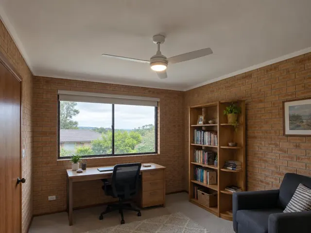 Ceiling fan in a brick-walled home office with window, desk and bookshelf in Caves Beach